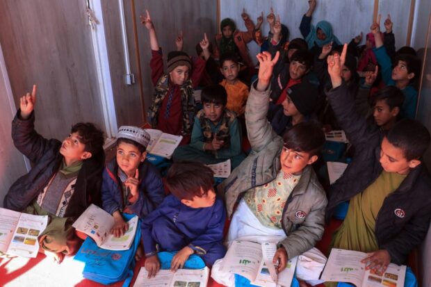 Afghan school children attend class at a makeshift school set in a container at Nayeb Rafi village of Zindah Jan district 