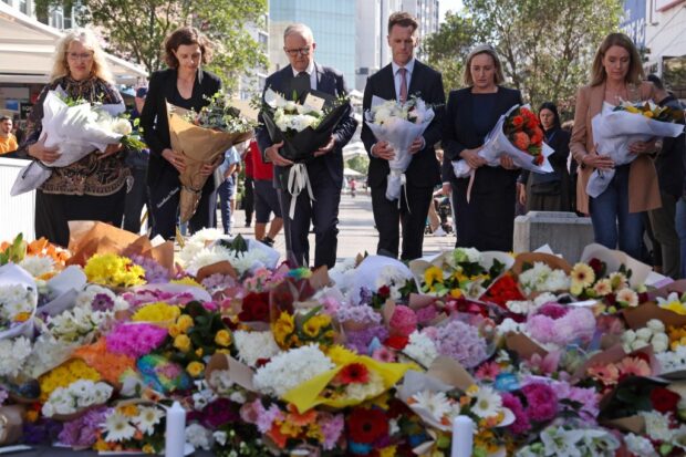 Australian Prime Minister Anthony Albanese (C) stands with New South Wales Premier Chris Minns (4th R) and other officials as they prepare to leave flowers outside the Westfield Bondi Junction shopping mall in Sydney on April 14, 2024,
