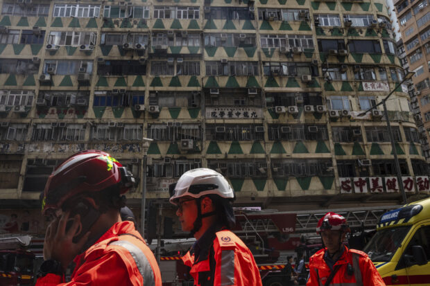 Ambulance workers walk past a building called New Lucky House where a fire started in Hong Kong, Wednesday