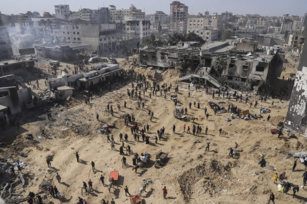 Palestinians walk through the destruction left by the Israeli air and ground offensive on the Gaza Strip