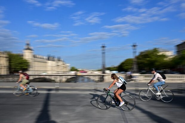 Local residents ride their bikes on a bridge in the center of Paris