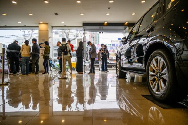 People queue to vote at a car showroom being used as a polling station in Seoul on April 10
