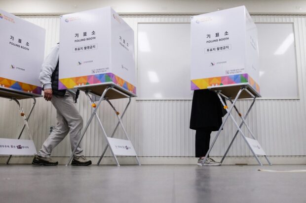 People fill in their ballots in booths at a polling station in Seoul on April 5, 2024