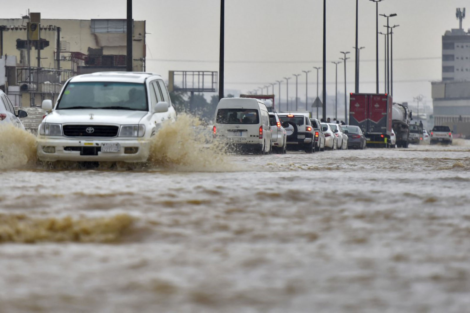 Cars drive through a flooded street following heavy rains in the Saudi coastal city of Jeddah on November 24, 2022, which delayed flights, forced school suspensions and closed the road to Mecca, Islam's holiest city. Jeddah, a city of roughly four million people positioned on the Red Sea, is often referred to as the "gateway to Mecca", where millions perform the hajj and umrah pilgrimages each year. Winter rainstorms and flooding occur almost every year in Jeddah, where residents have long decried poor infrastructure. (Photo by Amer HILABI / AFP)