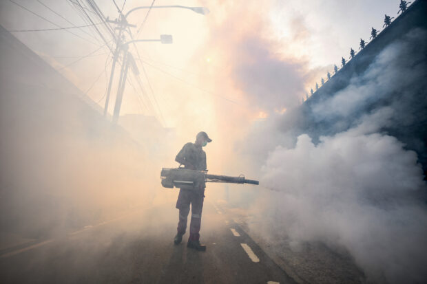 A pest control officer fumigates a street with insecticide in Jakarta on May 8, 2024 amid efforts to stop the spread of dengue fever by mosquitoes. Humans have made our planet warmer, more polluted and ever less hospitable to many species of animals, and these changes are driving the spread of infectious disease.