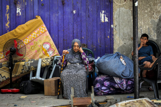 An elderly woman and child wait with belongings before evacuating from Rafah in the southern Gaza Strip on May 11, 2024 amid the ongoing conflict in the Palestinian territory between Israel and Hamas. (Photo by AFP)
