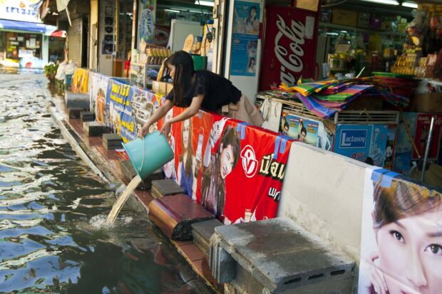 A woman empties water from her shop in Bangkok on November 10, 2011. The Thai capital, built on swampland, is slowly sinking and the floods currently besieging Bangkok could be merely a foretaste of a grim future as climate change makes its impact felt, experts say. 