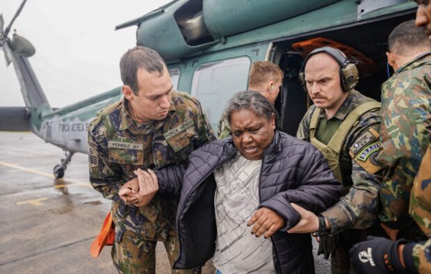 This handout picture released by the Brazilian Presidency shows a woman being assisted by members of the Air Force after being rescued in a helicopter from a flooded area of Rio Grande do Sul State