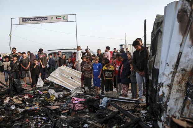 Palestinians look at the destruction after an Israeli strike where displaced people were staying in Rafah, Gaza Strip