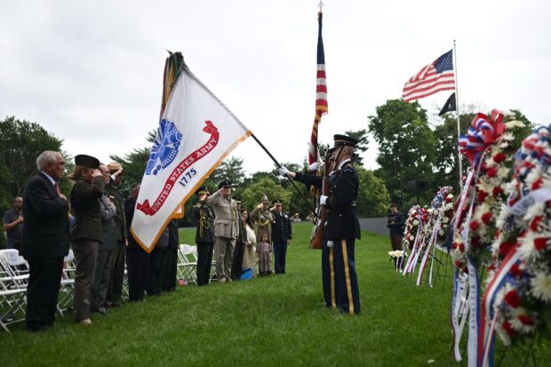 People stand at attention as members of the military present the colors during a Memorial Day ceremony at the Korean War Veterans Memorial in Washington, DC on May 27, 2024. 