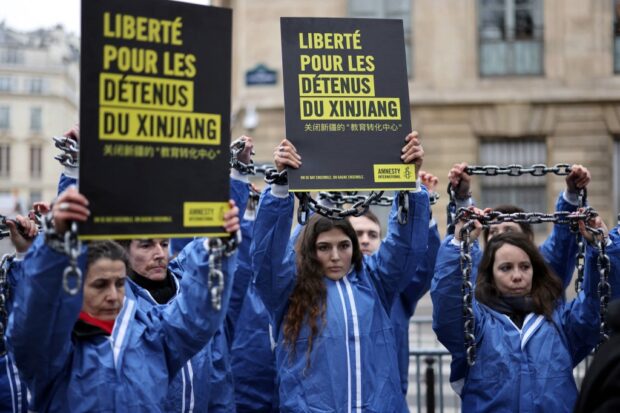 Amnesty International activists demonstrate outside the National Assembly in Paris, on January 26, 2022, to call for the opening by the French parliament of an inquiry over the human rights situation of Uyghurs in China.