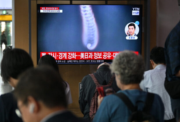 People watch a television screen showing a news broadcast with file footage of a North Korean missile test, at a train station in Seoul on July 1, 2024. North Korea on July 1, launched two ballistic missiles, South Korea's military confirmed -- the latest in a series of weapons tests by Pyongyang that have soured relations with Seoul. (Photo by Jung Yeon-je / AFP)