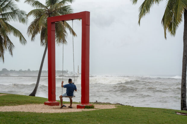 A man takes pictures with a phone at the malecon during high tide after Hurricane Beryl in Santo Domingo on July 2, 2024. Hurricane Beryl was hurtling towards Jamaica on July 2, as a monster Category 5 storm, after killing at least five people and causing widespread destruction in a deadly sweep across the southeastern Caribbean. 