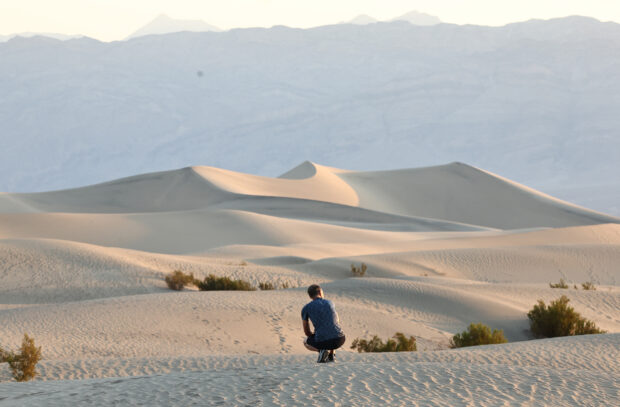 A visitor rests shortly after sunrise, when temperatures are less hot, at Mesquite Flat Sand Dunes during a long-duration heat wave which is impacting much of California on July 9, 2024 in Death Valley National Park, California. Park visitors have been warned, ‘Travel prepared to survive’ as temperatures are predicted to reach close to record highs this week. Death Valley is the hottest and driest place in the United States.  