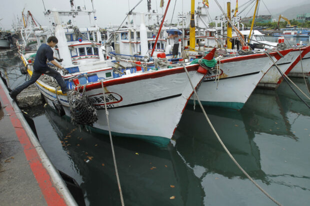 A fisherman leaps to his boat docked in harbor in Toucheng, north eastern Taiwan, Aug. 21, 2013. Taiwan said the Chinese coast guard boarded a Taiwanese fishing boat Tuesday, July 2, 2024, before steering it to a port in mainland China, and demanded that Beijing release the vessel. 