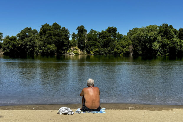 A man cools off by the river in Sacramento, Calif., Tuesday, July 2, 2024. Swaths of California sweltered Tuesday, and things were only expected to get worse during the Fourth of July holiday week for parts of the United States with nearly 90 million people under heat alerts.