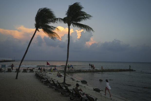 People lounge on the beach as the sun sets ahead of Hurricane Beryl's expected arrival, in Playa del Carmen, Mexico, Wednesday, July 3, 2024.