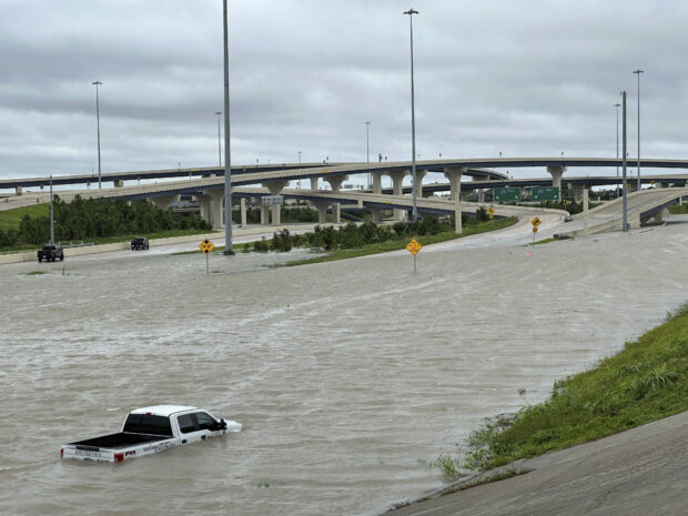 A vehicle is stranded in high waters on a flooded highway in Houston, on Monday, July 8, 2024, after Beryl came ashore in Texas as a hurricane and dumped heavy rains along the coast.