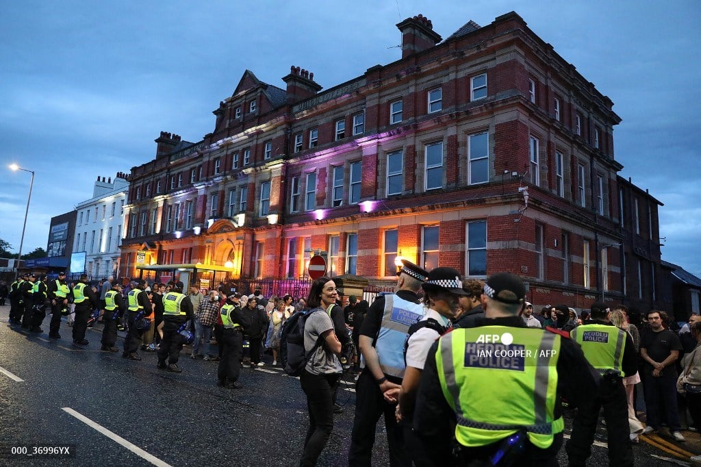 Police officers stand guard between protesters (back) defending the Abdullah Quilliam Mosque in Liverpool on August 2, 2024 against the 'Enough is Enough' demonstration (not seen) called in reaction to the fatal stabbings in Southport on July 29. UK police prepared for planned far-right protests and other demonstrations this weekend, after two nights of unrest in several English towns and cities following a mass stabbing that killed three young girls.