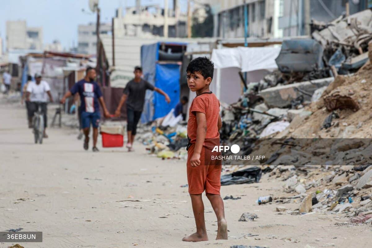 A Palestinian child walks barefoot along street riddled with rubbish and rubble in Khan Yunis, on the southern Gaza Strip 