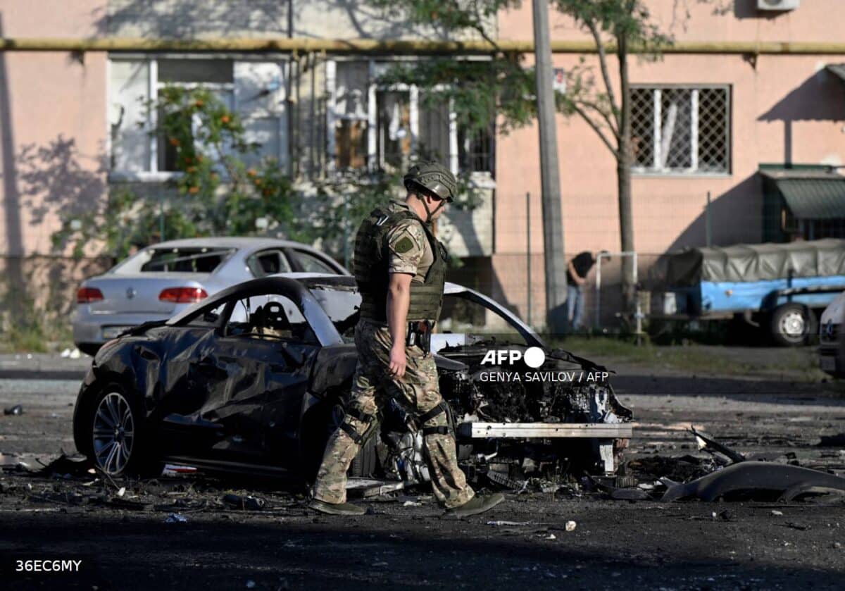 A police expert walks past a burned car at the site of a Russian strike in the city of Sumy on August 17, 2024, 