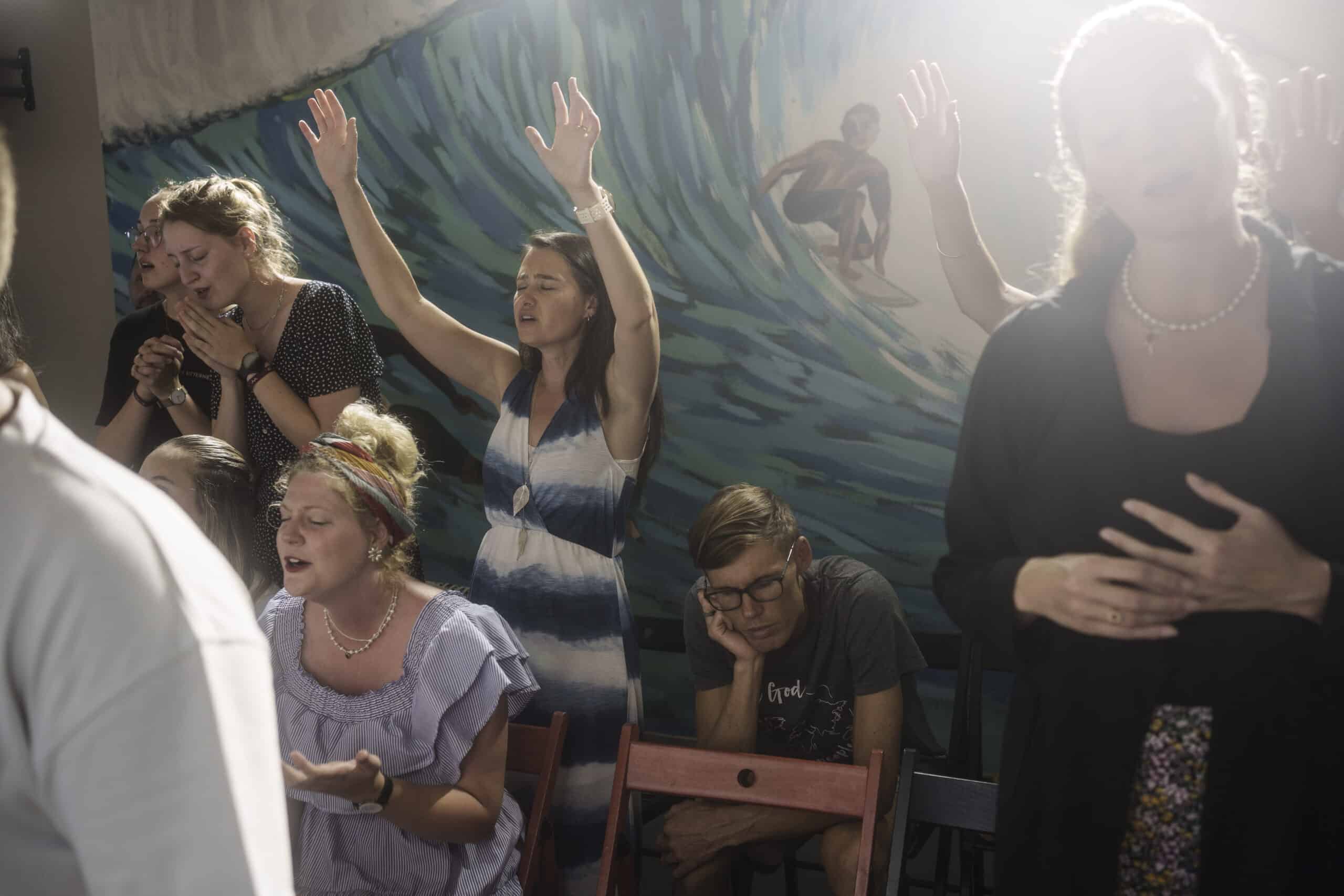 Marielle Louw, raised hands, and Andries Louw, missionaries from South Africa, pray during a worship service at Surf Church in Matosinhos beach in the suburbs of Porto, Portugal on Sunday, Aug. 18, 2024. (AP Photo/Luis Andres Henao)