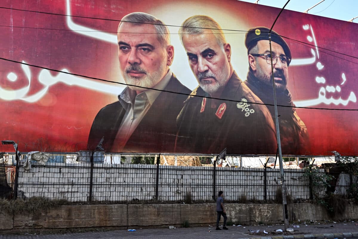 A man walks beneath a giant billboard showing pictures of the slain figures (L to R) Palestinian Hamas' political leader Ismail Haniyeh, Iran's Islamic Revolutionary Guard Corps' (IRGC) Quds Force commander Qasem Soleimani, and Lebanese Hezbollah's commander Fuad Shukr, along a road leading to Beirut International Airport on September 19, 2024. - Panic-stricken Lebanese have tossed power banks, and some sleep with mobile phones in another room, after hand-held devices used by Hezbollah operatives detonated two days in a row, killing 37 people.