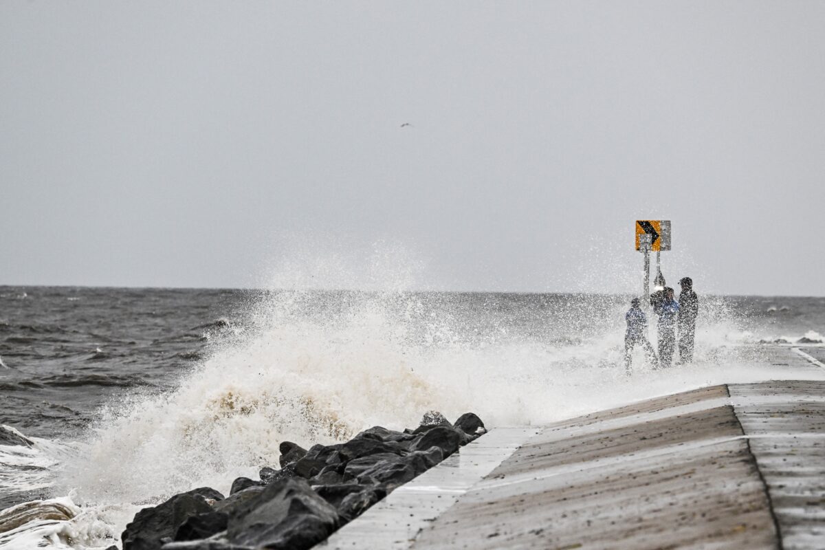 People stand on the shoreline ahead of the arrival of Hurricane Helene in Alligator Point, Florida, on September 26, 2024. - Parts of Florida face "unsurvivable" conditions when Hurricane Helene hits later Thursday, the US weather service said, warning that howling wind will drive destructive waves and storm surge as high as 20 feet (six meters) onto the low-lying coast.