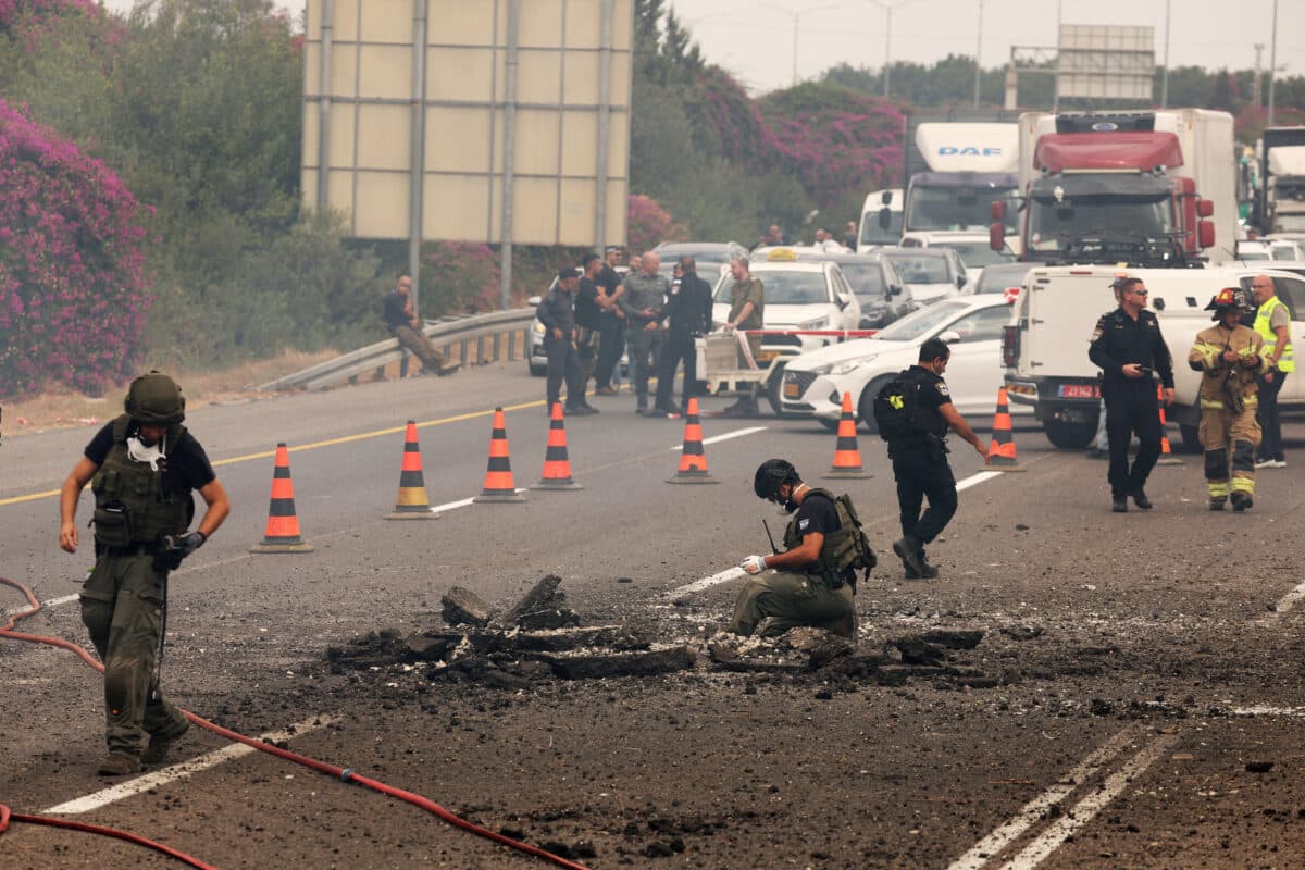 Israeli emergency and security personnel deploy at the impact site of a reported rocket fired from Lebanon, on the Horeshim interchange in central Israel on October 1, 2024. - Air raid sirens sounded in central Israel on October 1 and an AFP journalist heard explosions in the city of Tel Aviv, with the military saying projectiles had been fired from Lebanon. Police said one projectile hit a road near the central town of Kfar Kassen, wounding a man who was struck by shrapnel and treated by emergency services.