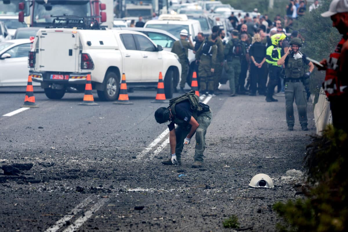 Israeli emergency and security personnel deploy at the impact site of a reported rocket fired from Lebanon, on the Horeshim interchange in central Israel on October 1, 2024. - Air raid sirens sounded in central Israel on October 1 and an AFP journalist heard explosions in the city of Tel Aviv, with the military saying projectiles had been fired from Lebanon. Police said one projectile hit a road near the central town of Kfar Kassen, wounding a man who was struck by shrapnel and treated by emergency services.