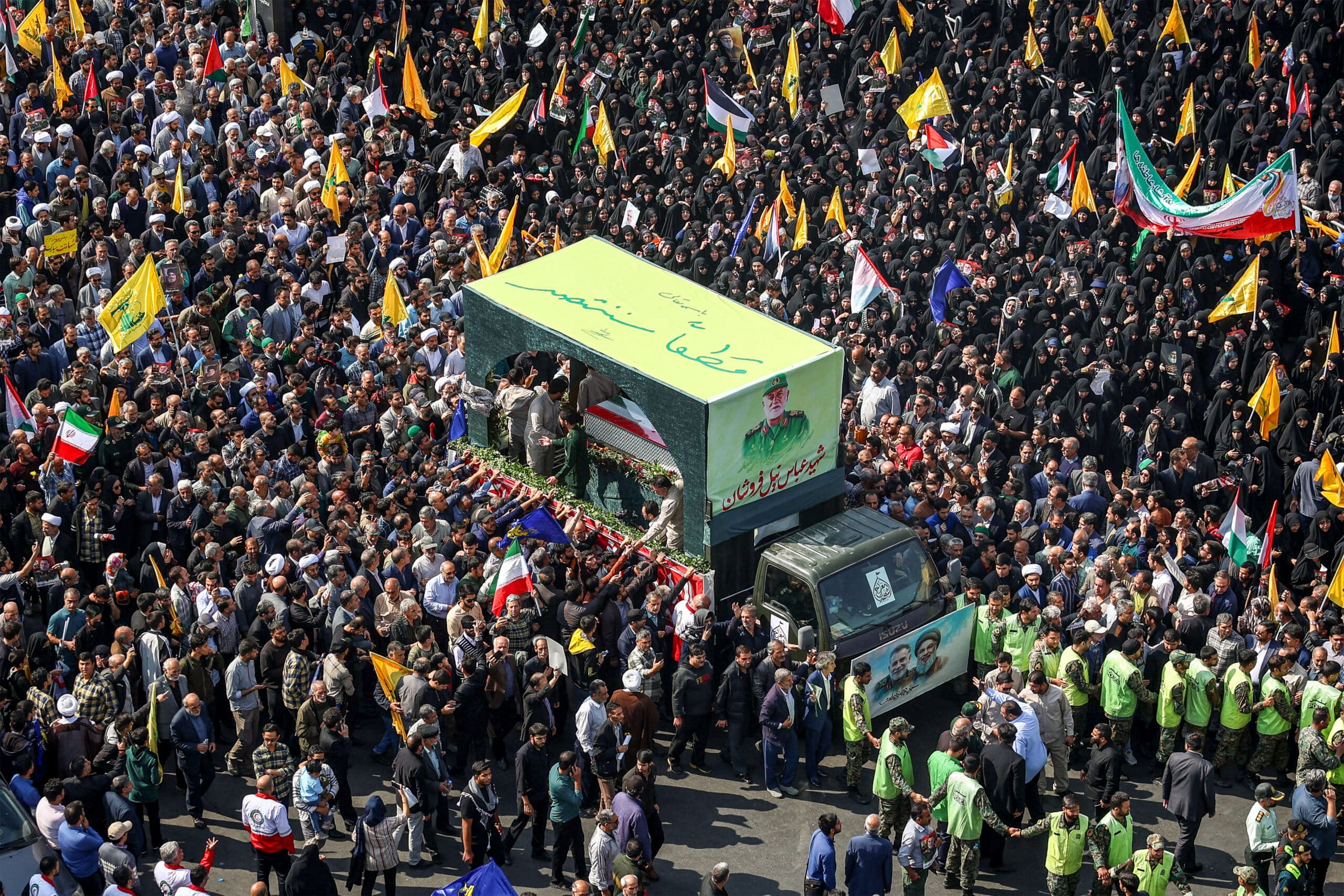 People gather around a vehicle bearing the Arabic slogan "surely we will be victorious" carrying the coffin of Abbas Nilforoushan, the slain commander of Iran's Islamic Revolutionary Guards (IRGC) who was killed in an Israeli air strike on Beirut's southern suburbs in late September, during his funeral procession in Mashhad in southern Iran on October 16, 2024. (Photo by Seyed Mohammad Alerasool / ISNA / AFP)