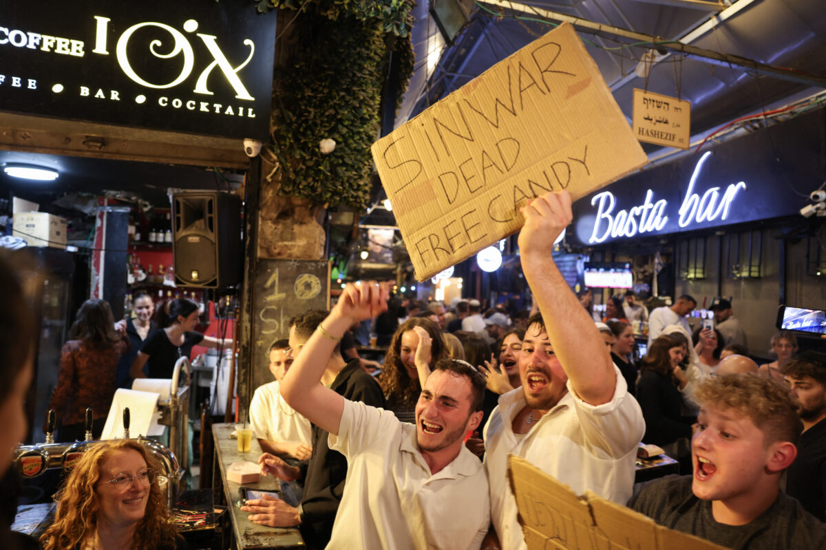 People hold placards as they celebrate the news of the death of Hamas leader Yahya Sinwar, in Jerusalem on October 17, 2024. - Israel said on October 17 its forces killed Sinwar, accused of masterminding the October 7, 2023 attack, calling it a "heavy blow" to the Palestinian group it has been fighting for more than a year.