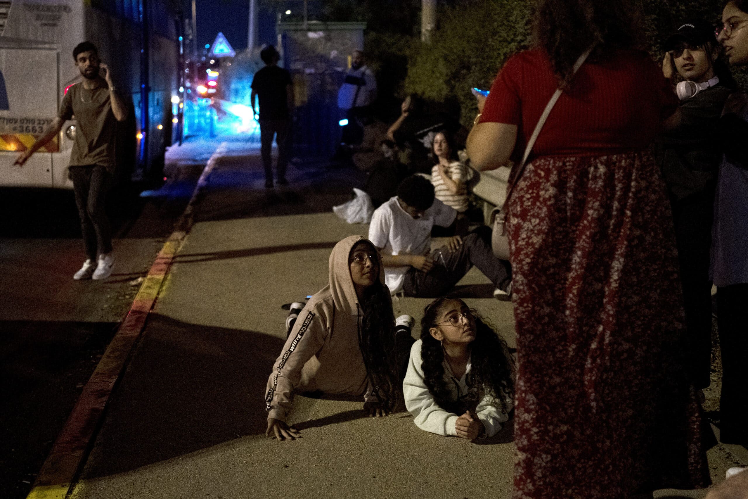 Israelis wait to re-board their bus after projectiles were launched from Iran are being intercepted in the skies over in Rosh HaAyin, Israel, Tuesday, Oct. 1, 2024. (AP Photo/Maya Alleruzzo)