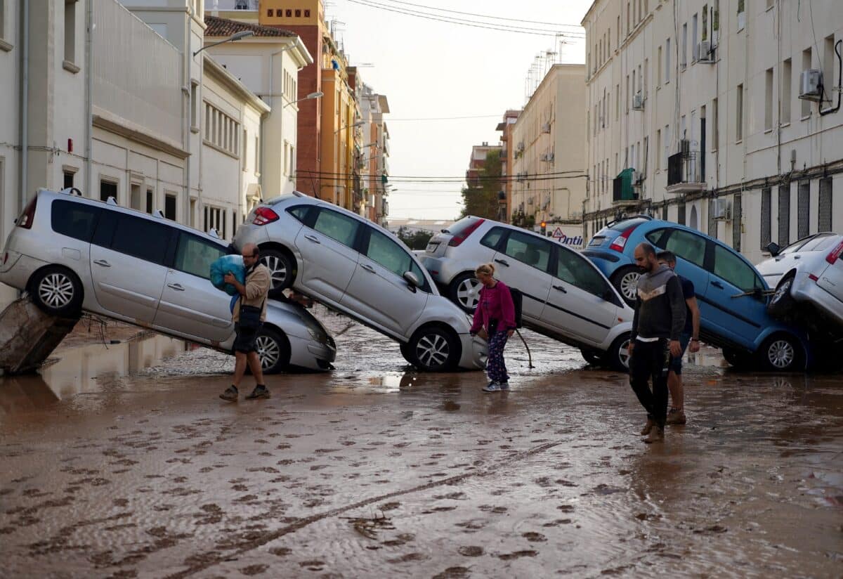 Residents walk past piled up cars following deadly floods in Valencia's De La Torre neighbourhood, south of Valencia, eastern Spain, on October 30, 2024. - Floods triggered by torrential rains in Spain's eastern Valencia region has left at least 70 people dead, rescue services said on October 30.