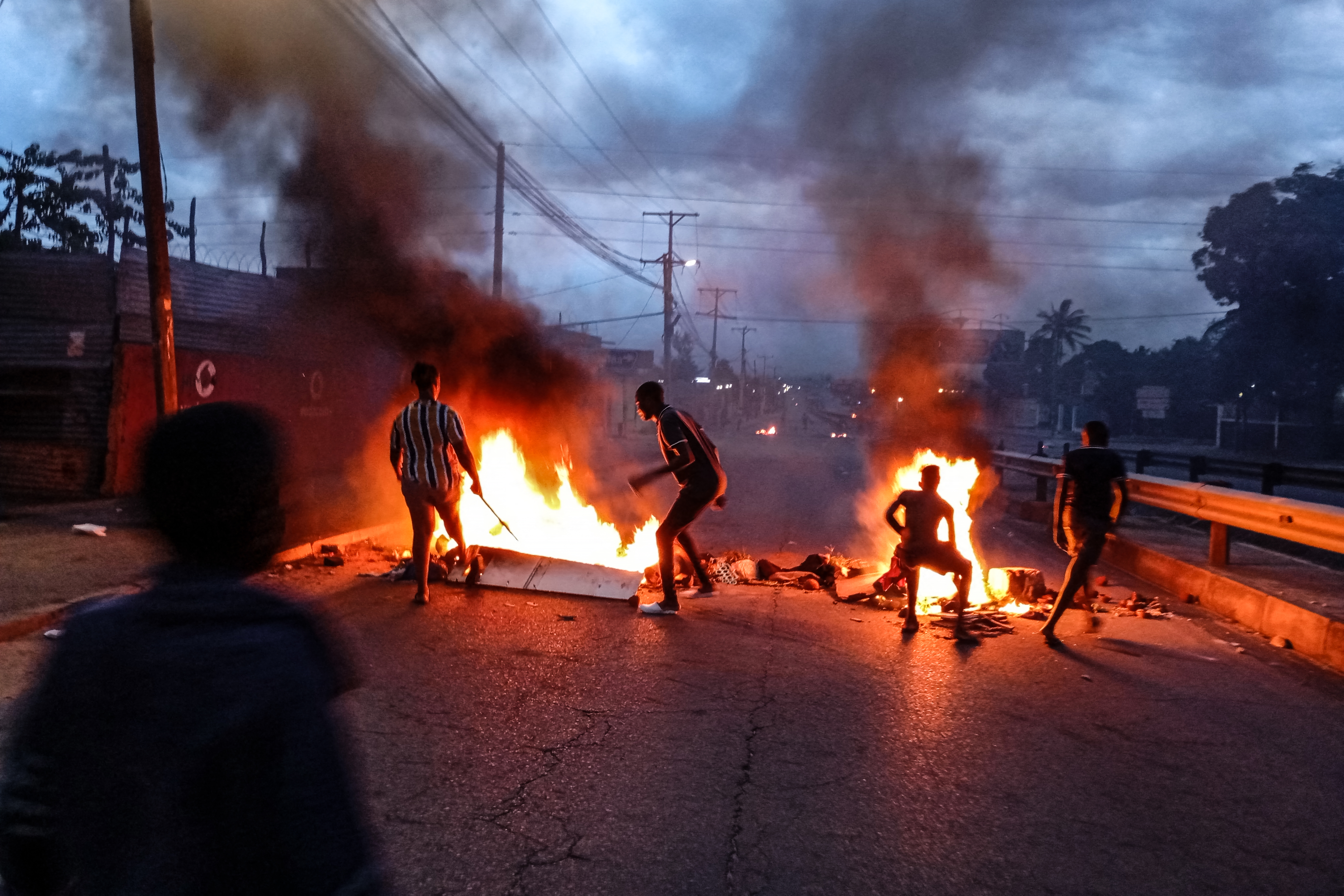 Protesters gather next to a burning barricade in Maputo on December 23, 2024. - Mozambique's highest court confirmed Monday the ruling party's victory in a disputed October vote after allegations of rigging triggered weeks of deadly street clashes. Fears are high that more violence could break out in the southern African nation after the opposition threatened to call an uprising following the decision. (Photo by Amilton Neves / AFP)