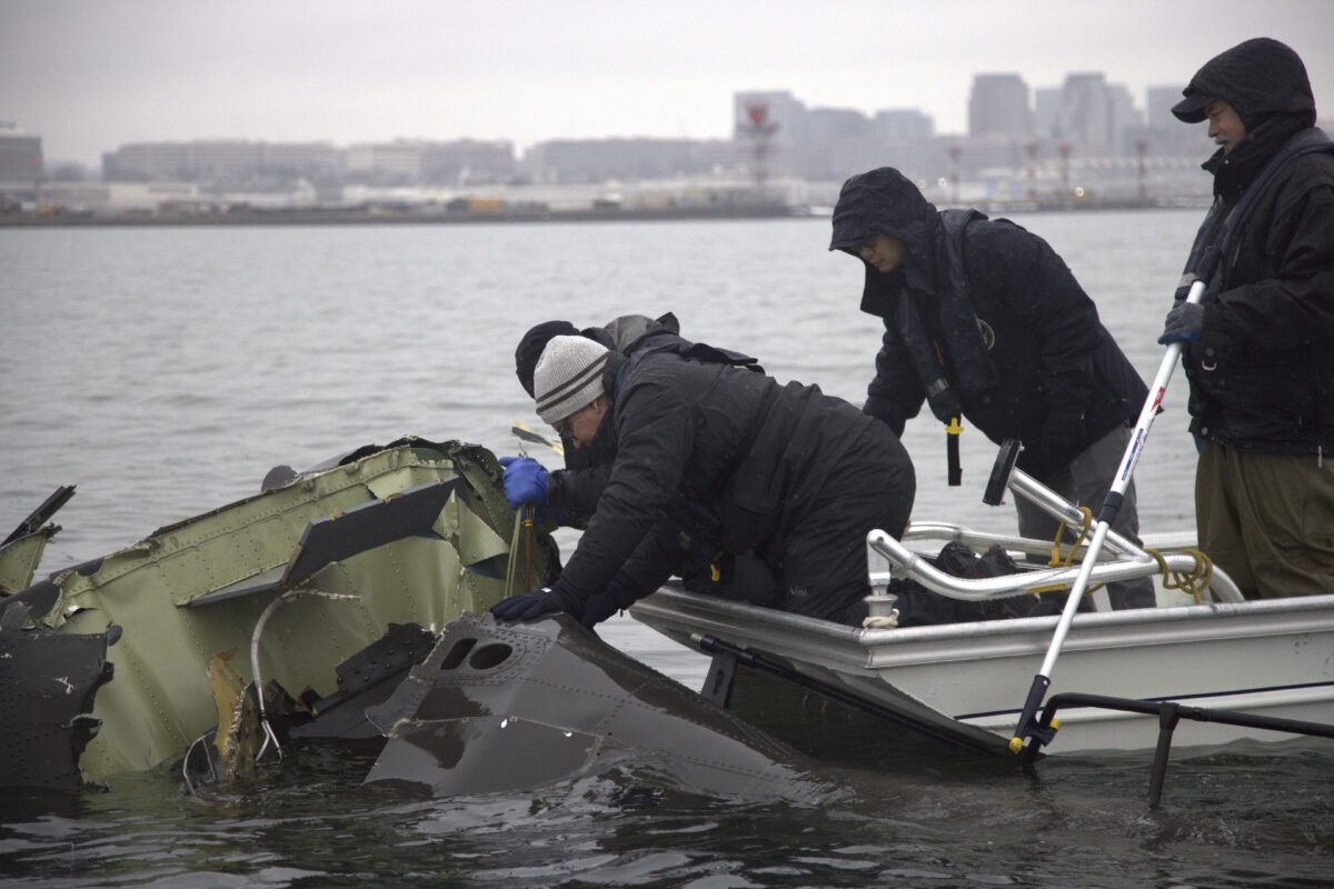 In this undated image provided by the National Transportation Safety Board, NTSB investigators and members of the salvage crew recover wreckage from the Army Black Hawk helicopter that collided with an American Airlines jet Wednesday night, Jan. 29, 2025, near Ronald Reagan Washington Na