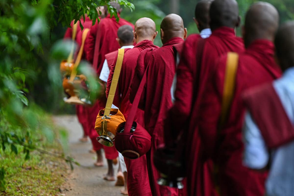 في هذه الصورة التي التقطت في 10 يونيو/حزيران 2025، يحمل رهبان بوذيون أوعية وهم يطلبون الصدقات من المصلين (أ ف ب، أرشيفية).