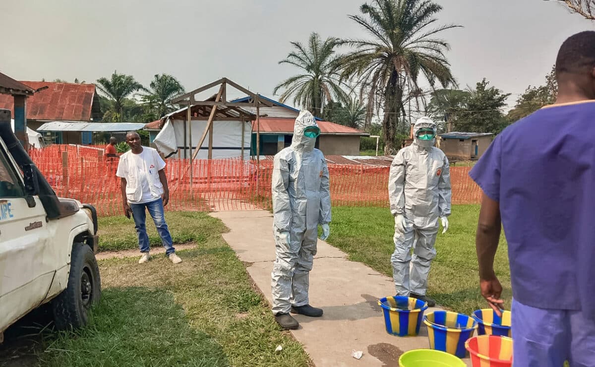 In this photo provided by Doctors Without Borders, men stand outside an Ebola treatment center in the remote Bulape Health Zone, Kasaï province, the Democratic Republic of Congo, Sunday, Sept 7, 2025, that was set up following the outbreak of the Zaire strain of the Ebola virus. (MSF via AP)